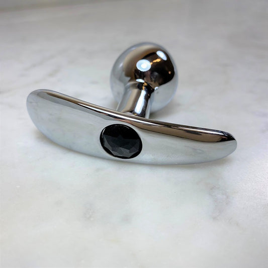 Zilverkleurige metalen buttplug met zwarte kristallen siersteen in de voet, detailopname