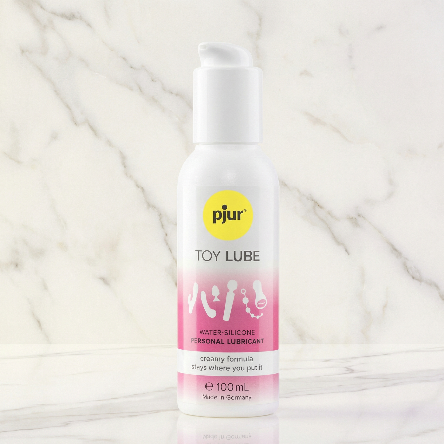 pjur Toy Lube 100 ml flesje met pompje op marmeren ondergrond, wit-roze etiket met geel logo