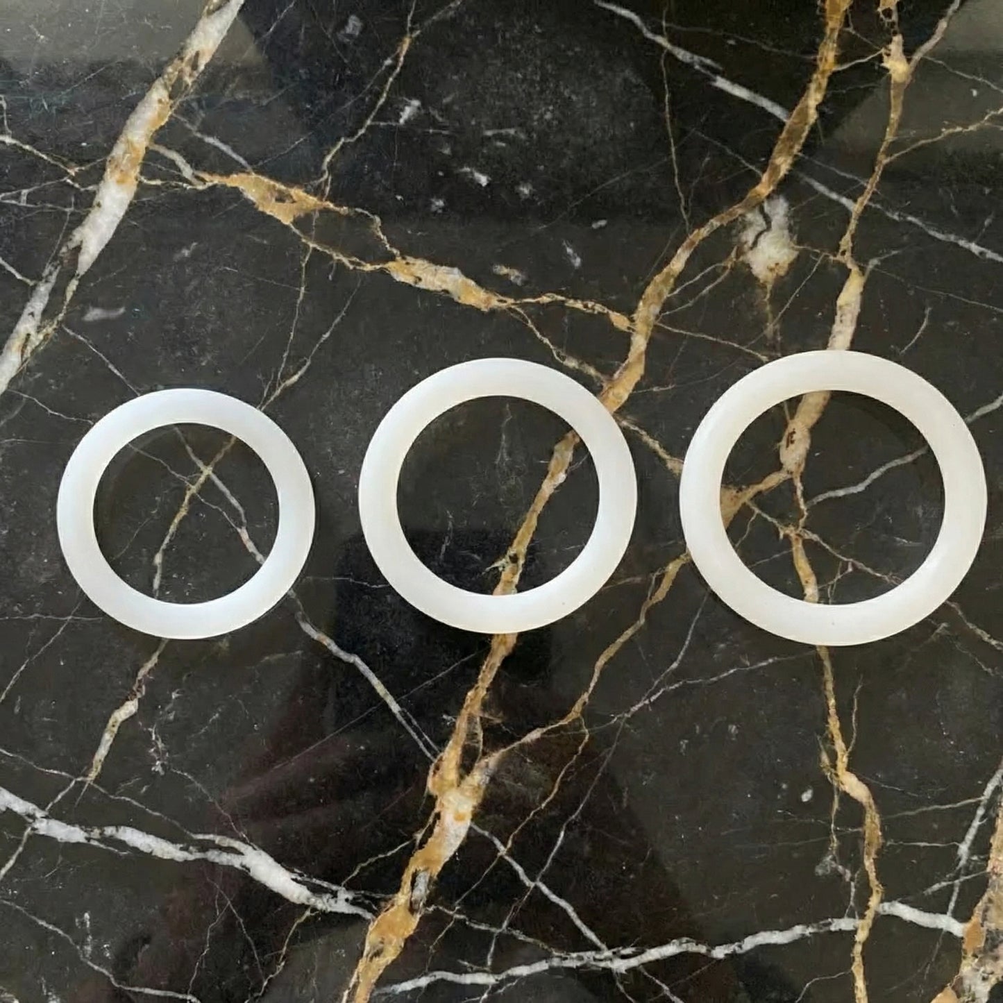 Witte cockring set van De Paarse Keizerin met drie verschillende maten op neutrale achtergrond