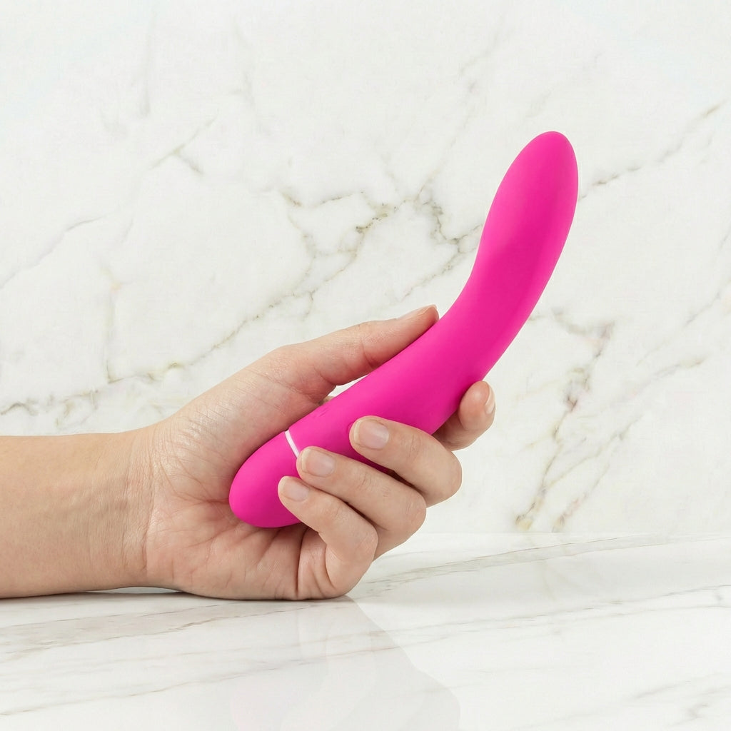 Hand die een roze gebogen Intimina Raya massager vasthoudt tegen witte marmeren achtergrond