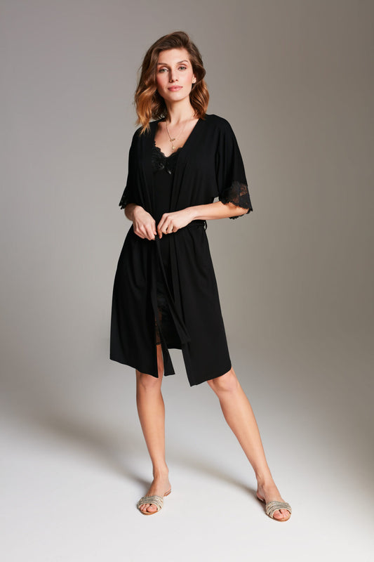 Vrouw in zwarte kimono-ochtendjas met kanten details over bijpassend zwart nachthemd