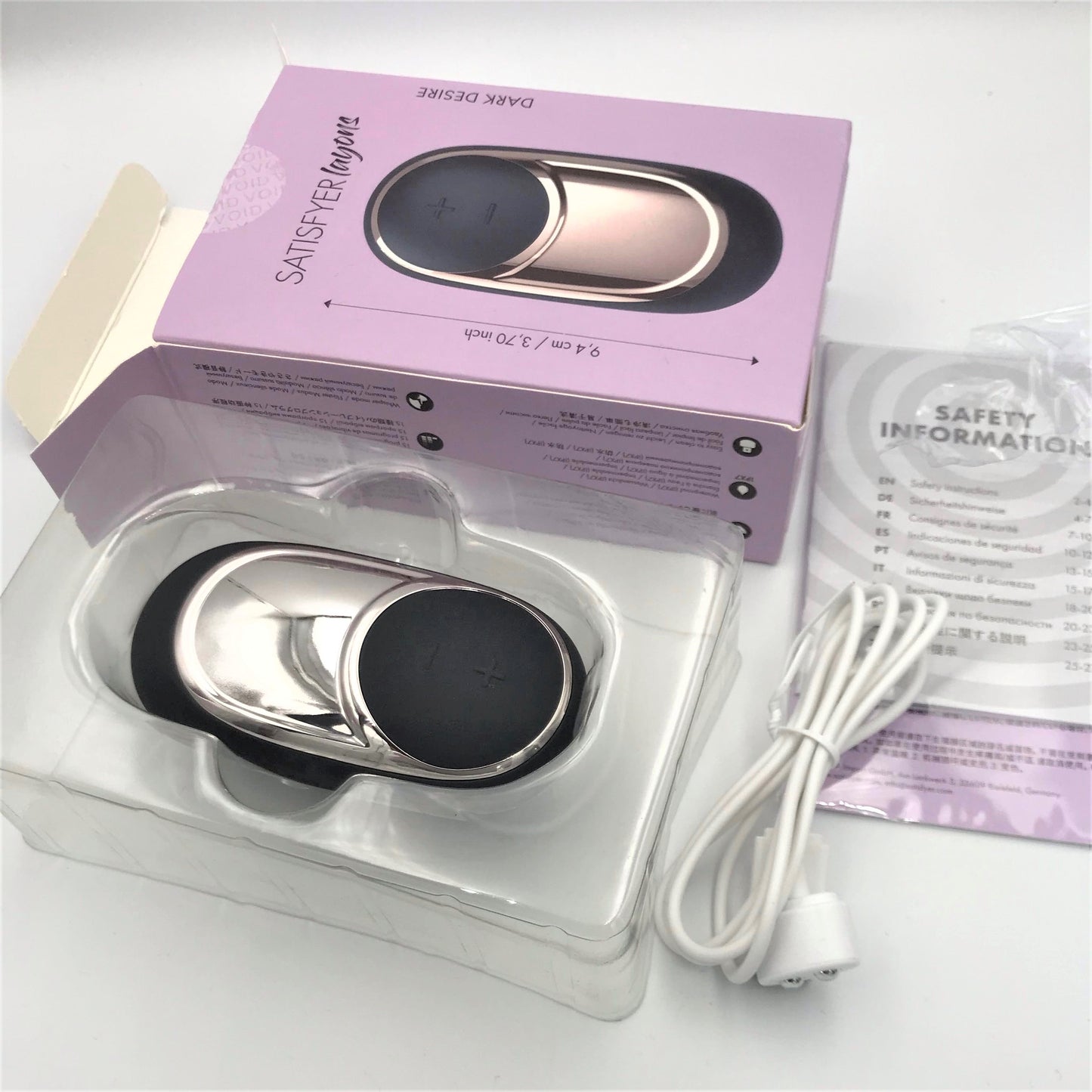 Uitgepakte Satisfyer Dark Desire Layons met doos, oplaadkabel en veiligheidsinformatie